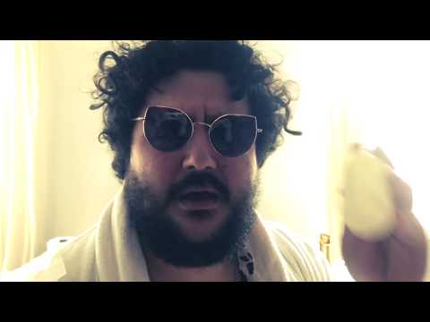 Homme barbu avec des lunettes noires et un fruit dans la main